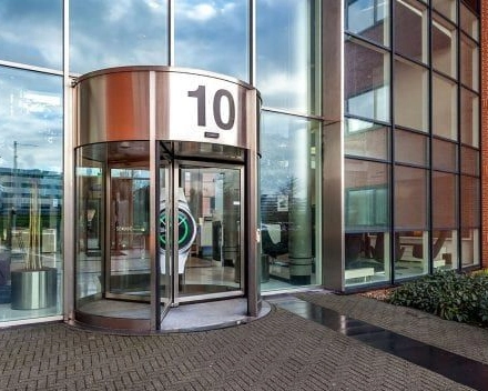 Hoofdingang van het kantoorpand op Olof Palmerstraat 10 in Delft met grote glazen gevel en draaideur, perfect voor diegene die kantoorruimte wil huren in een moderne omgeving.