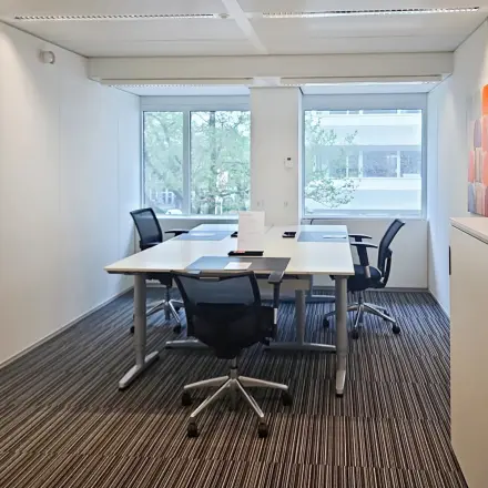 Moderne, lichte kantoorruimte aan Poortweg 4 in Delft met grote ramen, vier bureaus en comfortabele stoelen, ideaal voor kantoorruimte huren. De ruimte is netjes ingericht voor werk en vergaderingen.