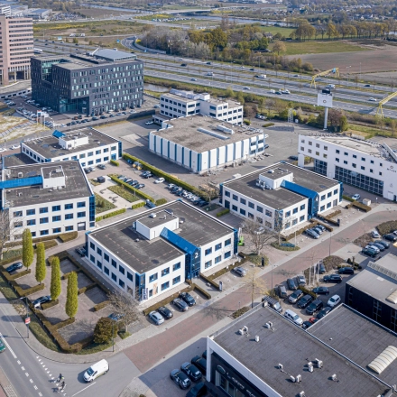 Luchtfoto van een kantoorgebouw op Europalaan 2 in Den Bosch, omringd door meerdere kantoren met parkeergelegenheid. Ideale locatie voor kantoorruimte huren.