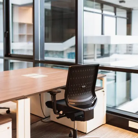Moderne kantoorruimte huren in Den Haag Centrum, met grote ramen die veel natuurlijk licht binnenlaten. Voorzien van een bureau en stoel, geschikt voor productief werken.