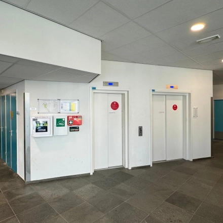 Ingang van het kantoorpand op Platinaweg 10 in Den Haag Escamp, met liften en heldere muren. Perfecte locatie voor kantoorruimte huren.