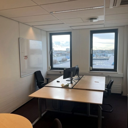 Kantoorruimte huren in kantoorpand op Platinaweg 10, Den Haag Escamp. Gezellige werkplek met twee bureaus en stoelen, grote ramen voor natuurlijk licht. Ideaal voor productief werken.