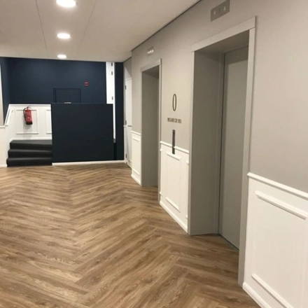 Een moderne, goed verlichte kantoorruimte met houten vloer, twee liften en een trap aan de Johan de Wittlaan 3-7, Den Haag Statenkwartier, ideaal voor kantoren te huur.