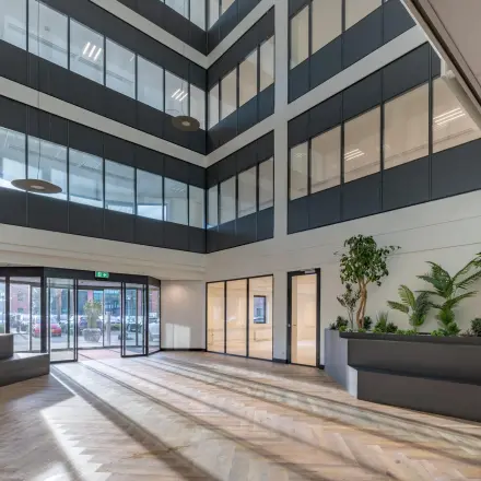 Lichte kantoorentree met houten vloer, grote ramen en moderne plantenbakken in kantoorpand op Wisselwerking 40-48 in Diemen.