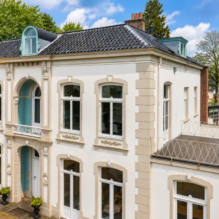 Gevel van een statig kantoorpand aan de Dorpsstraat 77 in Doorn met klassieke details en grote ramen, ideaal voor het huren van een kantoorruimte.