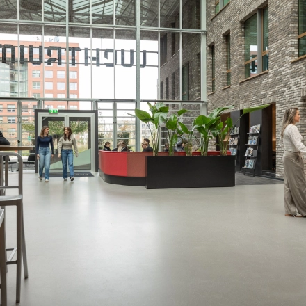 Moderne en lichte kantoorruimte op Flight Forum 120-159, Eindhoven Airport. Mensen wisselen ideeën uit bij het koffiepunt. Perfecte plek voor je volgende kantoor om te huren.