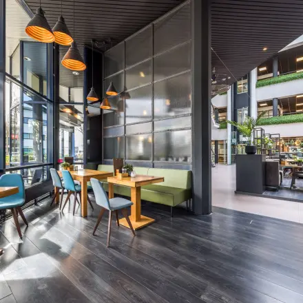 Kantoorruimte met moderne tafels en stoelen bij Luchthavenweg 81, Eindhoven Airport, met grote ramen en veel lichtinval.