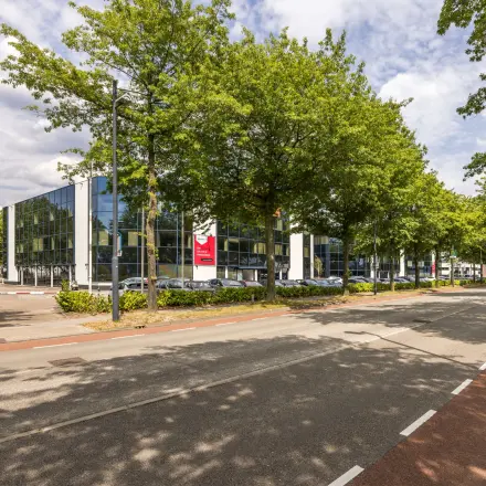 Modern kantoorpand aan Luchthavenweg 81, Eindhoven Airport, omgeven door groen en voorzien van eigentijdse architectuur. Een ideale locatie voor kantoorruimte huren in een inspirerende zakelijke omgeving.