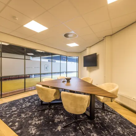 Stijlvolle kantoorruimte huren aan Luchthavenweg 81, Eindhoven Airport. Moderne vergadertafel met comfortabele stoelen in een lichte omgeving. Perfect voor zakelijke gesprekken en vergaderingen.