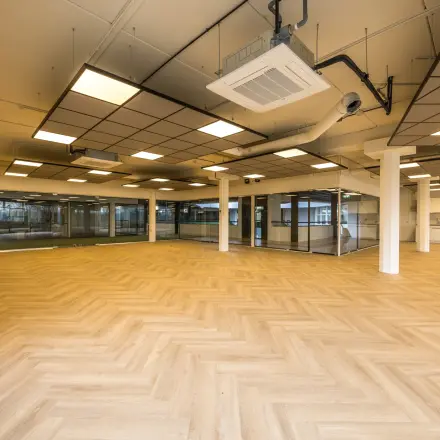 Ruime lege kantoorruimte op Luchthavenweg 81, Eindhoven Airport, met houten vloer en groot raam voor veel lichtinval. Ideaal voor wie een modern en aanpasbaar kantoorpand wil huren.
