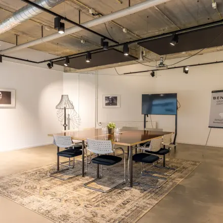 Stijlvol ingerichte kantoorruimte op Luchthavenweg 81, Eindhoven Airport, met een vergadertafel, stoelen en kunstwerken aan de muur. Perfect om te huren voor diverse zakelijke activiteiten.
