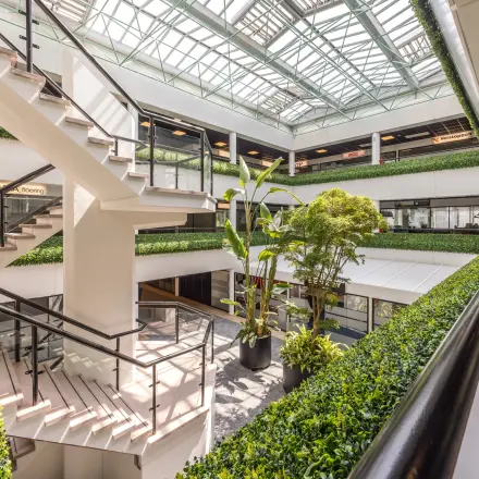 Ruim atrium van het kantoorpand op Luchthavenweg 81, Eindhoven Airport, met veel groen en open trappenhuis. Ideaal voor kantoorruimte huren met een moderne uitstraling.