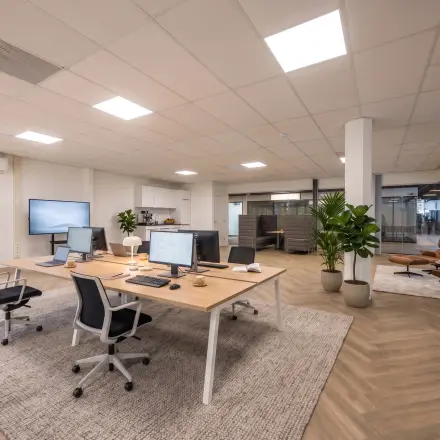 Ruime en moderne kantoorruimte met open werkplekken en comfortabele stoelen bij Eindhoven Airport, perfect voor wie op zoek is naar kantoorruimte huren. Strakke inrichting en veel natuurlijk licht.