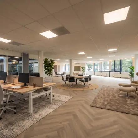 Ruime kantoorruimte met moderne werkplekken, comfortabele stoelen en grote ramen, ideaal voor kantoorruimte huren bij Eindhoven Airport.