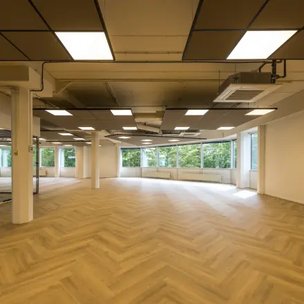 Ruime en lichte kantoorruimte op Eindhoven Airport met een modern plafond ontwerp en grote ramen voor natuurlijk licht.