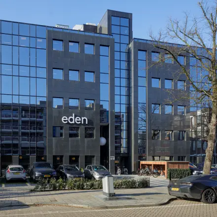 Glazen en moderne uitstraling van het kantoorpand aan de Paradijslaan 30-38 in Eindhoven Centrum, omringd door geparkeerde auto's. Ideale locatie voor het huren van kantoorruimte.
