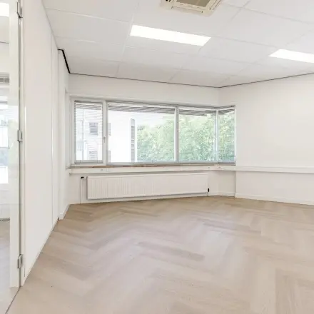 Lichte, open kantoorruimte op Croy 7, Eindhoven De Hurk met grote ramen en stijlvolle laminaatvloer, ideaal voor bedrijfshuur.