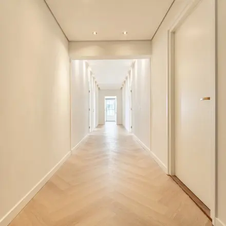 Verlichte gang in een kantoorpand op Croy 7, Eindhoven De Hurk. De gang heeft een houten visgraatvloer en deuren aan weerszijden. Perfecte locatie voor kantoorruimte huren.