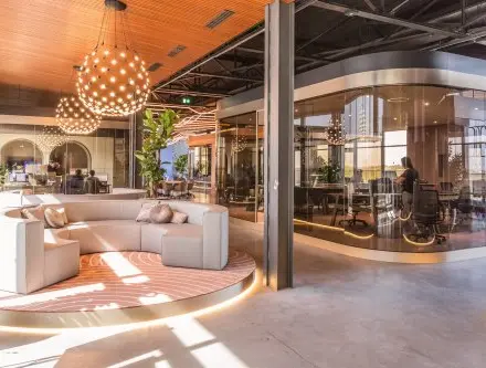 Moderne kantoorruimte huren in kantoorpand op Achtseweg Zuid 159R, Eindhoven Strijp-S, met stijlvolle meubels en grote ramen. Personen werken in een vergaderruimte en open werkplekken.