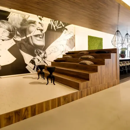 Modern ingerichte kantoorpand met houten trappen, kunst aan de muur en stijlvolle hanglampen op Frederiklaan 10E, Eindhoven Strijp-S. Ideaal voor bedrijfscultuur met ruimte voor creativiteit en bijeenkomst.