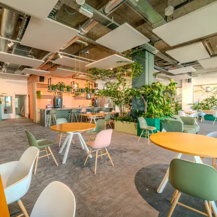 Lichte en groene werkplek in Eindhoven Strijp-S met moderne inrichting en veel planten. Ideale kantoorruimte huren met ronde tafels en comfortabele stoelen.