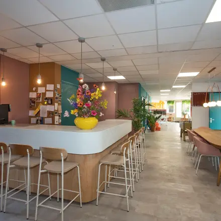 Lichte, modern ingerichte kantoorruimte met een grote tafel, stoelen en een bar op Boddenkampsingel 95 in Enschede, perfect voor het huren van een inspirerende werkplek.