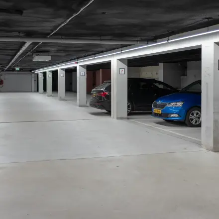 Ondergrondse parkeergarage in kantoorpand op Kuipersdijk 2-4, Enschede met betonnen muren en meerdere geparkeerde auto's.