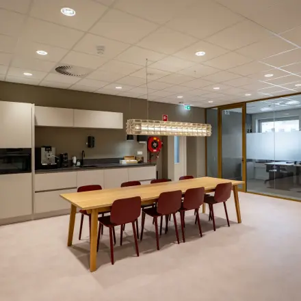 Moderne keuken in kantoorpand op Kuipersdijk 2-4, Enschede met ruime tafel en stoelen, ideaal voor huur als werkruimte.
