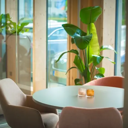 Moderne kantoorruimte huren aan Moutlaan 1-23, Enschede met stijlvolle ronde tafel, comfortabele stoelen en groen decor voor een inspirerende werkervaring.
