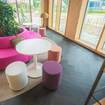 Moderne kantoorruimte met kleurrijke zitgelegenheid en veel natuurlijk licht op Moutlaan 1-23 in Enschede, perfect om te huren. Planten en houten decor zorgen voor een uitnodigende sfeer.