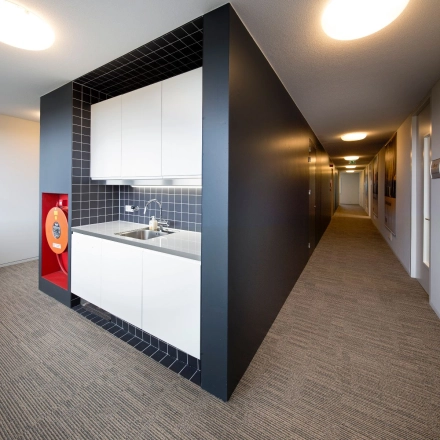 Compacte pantry in een kantoorruimte aan de Transportlaan 1-151, Geleen, met moderne zwarte tegels en witte kasten. Ideaal voor huurders die een functionele pauzeplek in een kantoorpand zoeken.