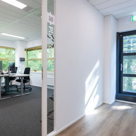 Kantoorruimte aan Groningenweg 8 8, Gouda met moderne bureaus, stoelen, en veel natuurlijk licht. Geschikt voor bedrijven die een kantoorpand willen huren.