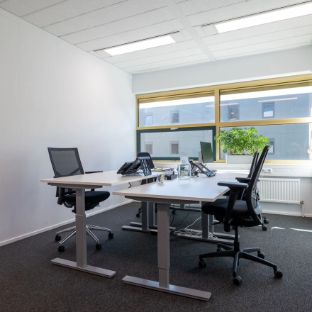 Verlichte kantoorruimte in Gouda met vier bureaustoelen en een groot raam, ideaal om te huren voor efficiënte werkplekken.