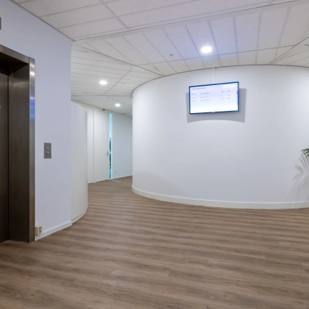 Ruime, lichte entree van een kantoorpand op Groningenweg 8 8 in Gouda met een moderne houten vloer, strakke witte muren en een lift. Ideaal voor kantoorruimte huren.