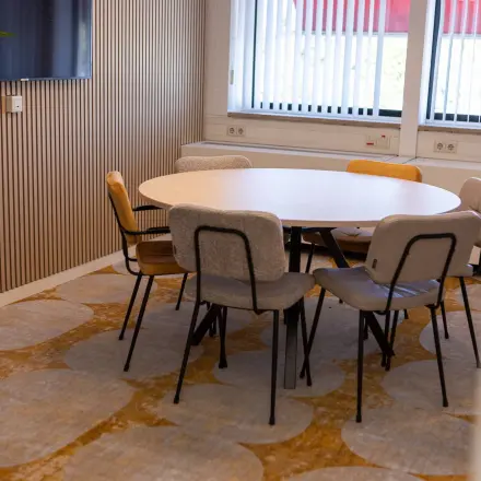 Gezellige vergaderruimte in een kantoorpand op Atoomweg 6B, Groningen met een ronde tafel omringd door diverse stoelen.