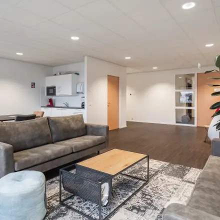 Ruime kantoorpand op Mollerusweg 84 in Haarlem Waarderpolder, met moderne zitbanken, een stijlvolle tafel, en een kleine keukenhoek. Ideale kantoorruimte huren voor informele vergaderingen of ontspanning.