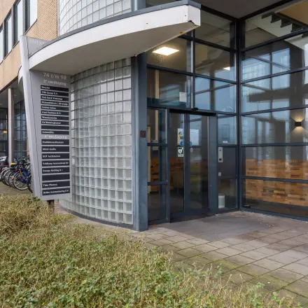 Moderne entree van een kantoorpand op Mollerusweg 84 in Haarlem Waarderpolder, met glazen gevel en fietsrekken. Ideaal voor wie kantoorruimte wil huren in een levendig gebied.