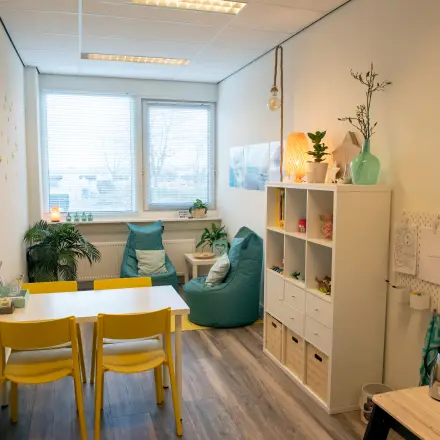 Gemeubileerde kantoorruimte te huur op Waarderweg 19 in Haarlem Waarderpolder, met een kleine tafel, felgekleurde stoelen en decoratieve elementen.