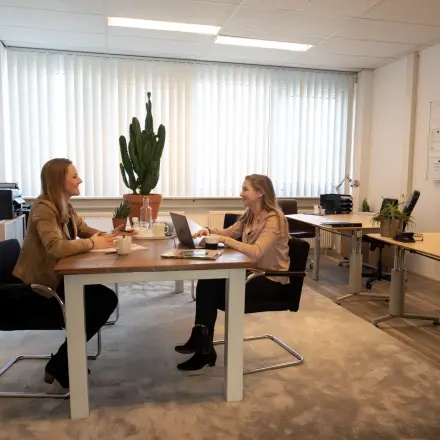 Kantoorruimte te huur op Waarderweg 19 in Haarlem Waarderpolder, met twee mensen die aan een bureau werken in een gemeubileerd kantoor met planten en kantoorpand inrichting.
