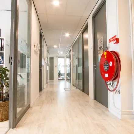 Heldere kantoorruimte op Waarderweg 19 met glazen deuren en een modern interieur. Kantoorunits en een rek met kantoorbenodigdheden langs de muur.
