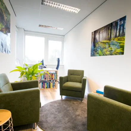 Kantoorruimte huren aan de Waarderweg 19 in Haarlem Waarderpolder, met drie groene fauteuils, een boekenkast en grote ramen, ideaal voor vergaderingen of als werkplek.