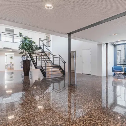 Ruime entree in het kantoorpand aan de Steenovenweg 5 in Helmond, met glazen gevels en een moderne trap. Ideaal voor wie kantoorruimte wil huren in een professionele omgeving.