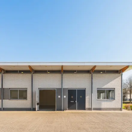 Exterieur van een kantoorpand op Steenovenweg 5 in Helmond, geschikt voor kantoorruimte huren. Bakstenen gevel met moderne ramen en een inrit.