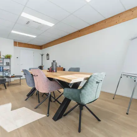 Moderne kantoorruimte aan de Steenovenweg 5 in Helmond, met vergadertafel, stoelen en een flip-over. Ideaal voor kantoorruimte huren of vergaderdoeleinden.