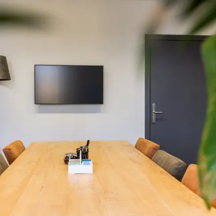 Stijlvolle kantoorruimte huren op Demmersweg 3 in Hengelo met een houten tafel, comfortabele stoelen en een moderne lamp.