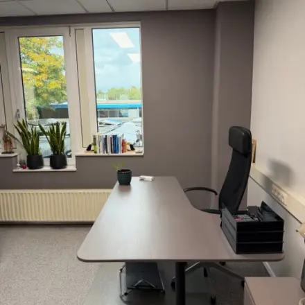 Kantoorruimte huren op Hamerstraat 10, Hengelo. Een strak ingerichte ruimte met bureaus, een comfortabele stoel en uitzicht op de buitenomgeving.