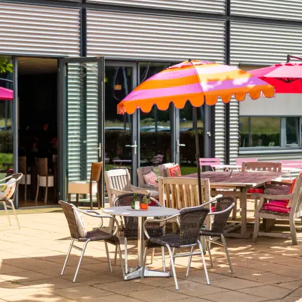 Buitenterras met kleurrijke parasols en diverse zitplaatsen aan Jan Tinbergenstraat 202, ideaal voor een pauze tijdens het kantoorruimte huren in Hengelo.