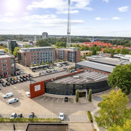 Luchtfoto van het kantoorpand op Lintelerweg 40 in Hengelo, omgeven door parkeerplaatsen en groene bomen. Ideale locatie voor kantoorruimte huren in een levendige omgeving.