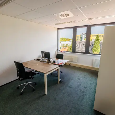 Lichte kantoorruimte te huur op Welbergweg 60, Hengelo met twee bureaus, comfortabele stoelen en groot raam voor natuurlijk licht.