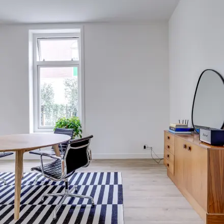 Kantoorruimte huren op Graaf Florislaan 40, Hilversum met een licht interieur, ronde tafel, moderne stoelen en een kast met spiegel.